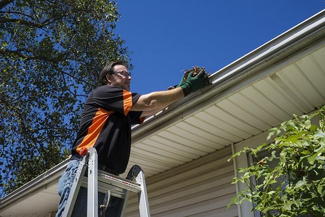 a repairman working on a broken gutter system in Highland Heights
